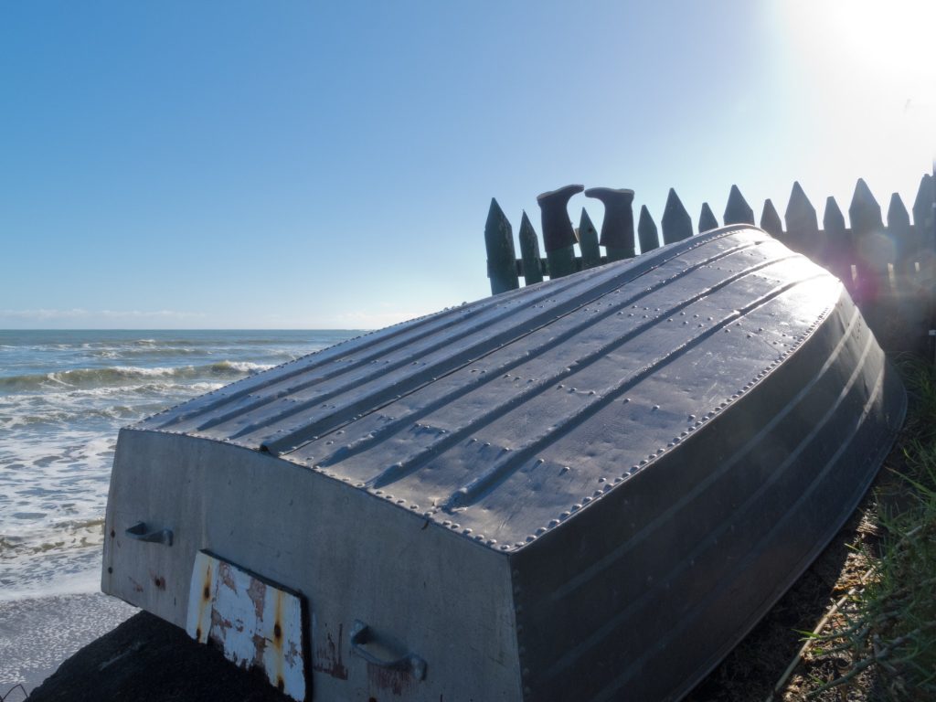 Aluminum fishing boat and boots drying on fence
