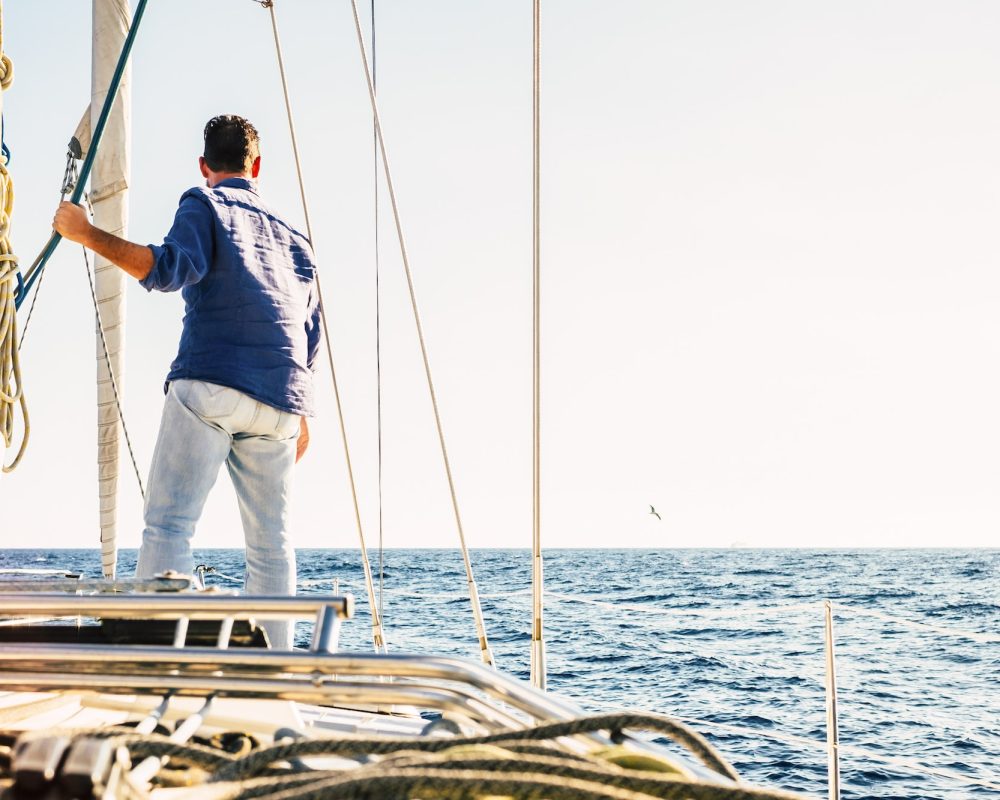 Sailing activity people - man viewed from back stand up on the deck